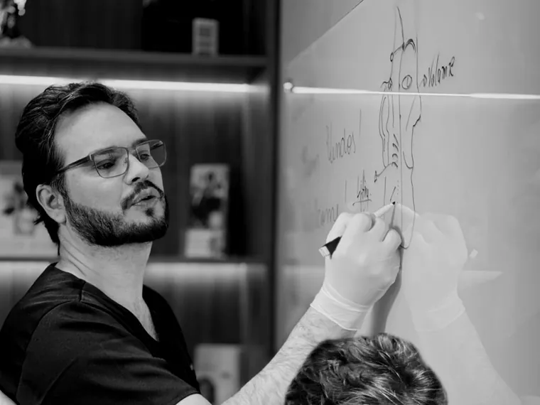 Preceptor desenhando o planejamento do caso no quadro, com aluna ao lado.